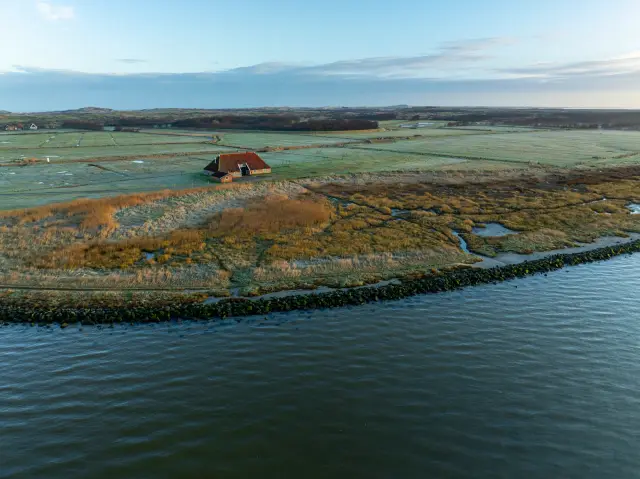Aerial of a solitary barn beside a polder waterline at first light