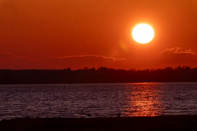 The sun setting over calm Scottish coastal water.