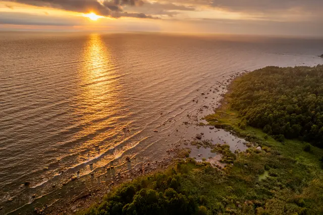 An aerial view of the coast under a golden sunset.