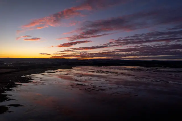 An aerial view of the Norwegian coast under a pink twilight sky.