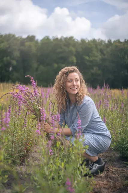 A woman standing in a flowering summer field.