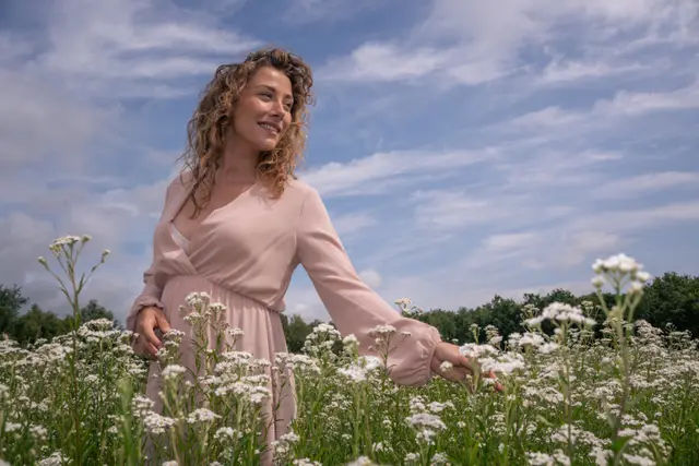 A woman in a pink dress among tall wildflowers.
