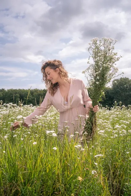 A woman gathering wildflowers in a meadow.
